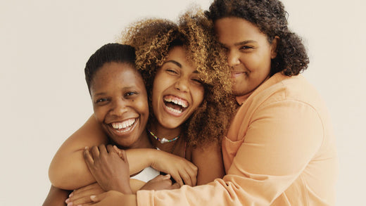 Trois femmes souriantes qui se tiennent dans les bras 
